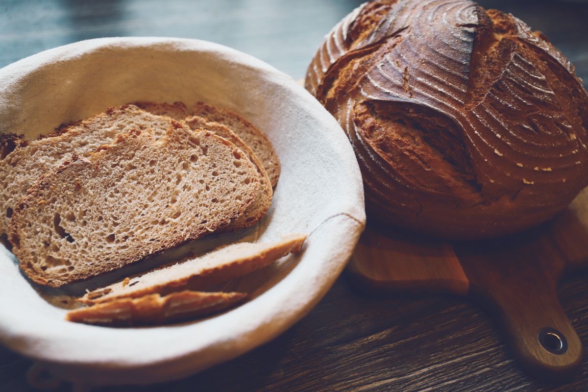 A round proofing basket beside a sourdough boule showing the spiral rings a banneton leaves.