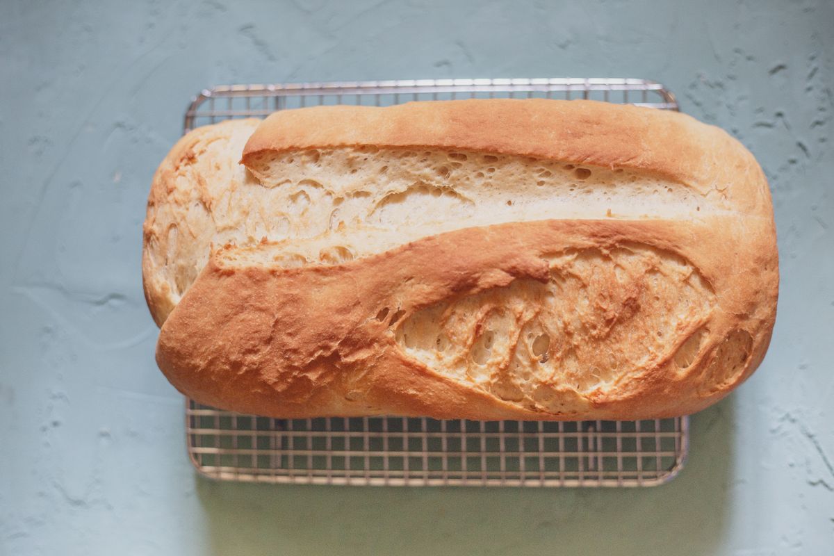 A golden homemade sandwich loaf cooling on a wire rack.