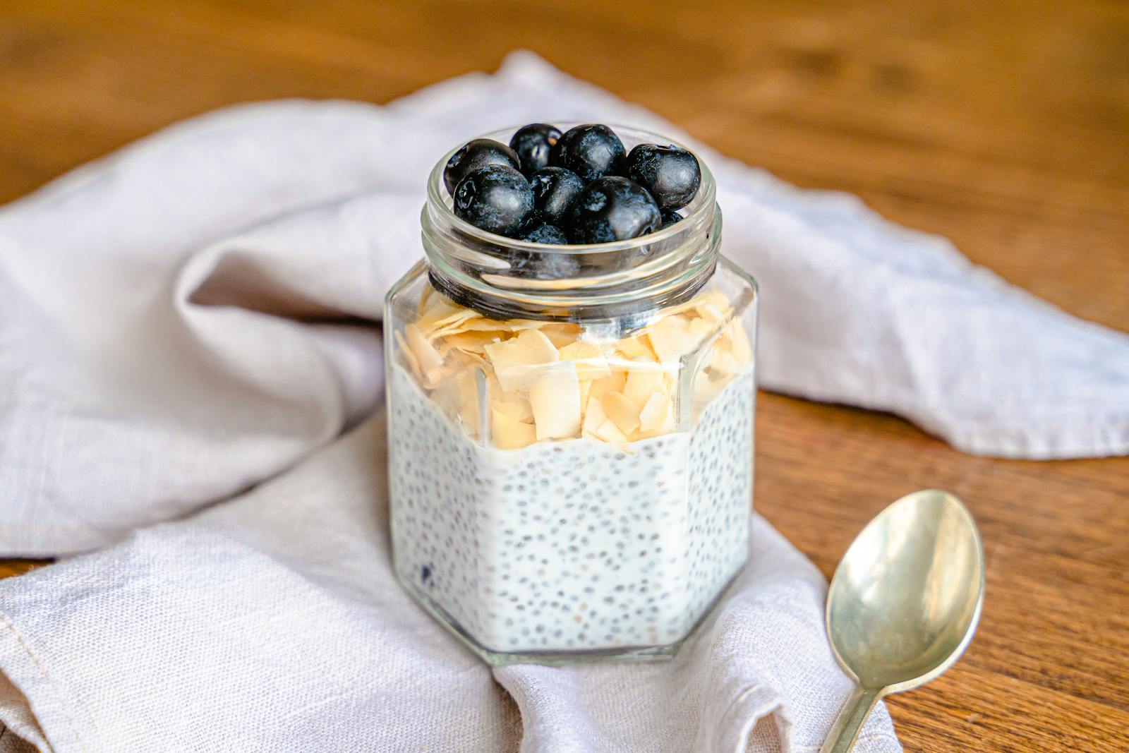 Chia pudding in a glass jar topped with blueberries and almond flakes