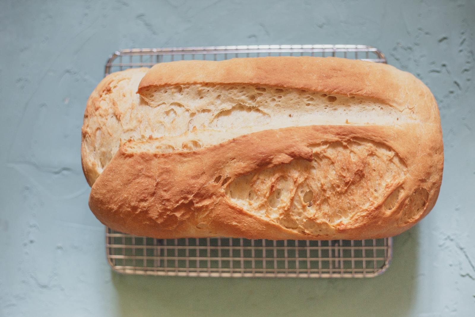 A golden brown homemade einkorn-style bread loaf cooling on a wire rack, showing the distinct yellow-amber color einkorn flour gives to baked goods.