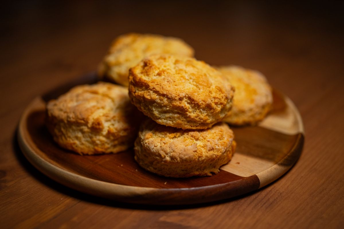 Freshly baked golden biscuits stacked on a wooden plate.
