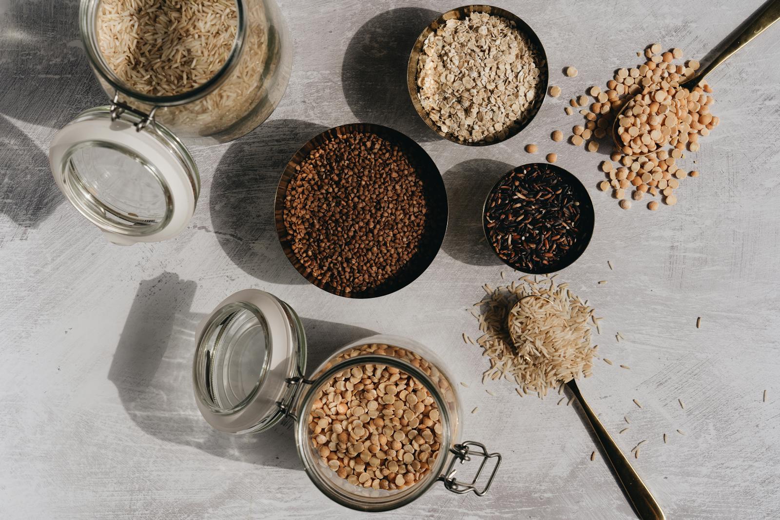 A top-down view of assorted grains and pulses in glass jars and bowls, the kind of gluten-free pantry this guide helps you build.
