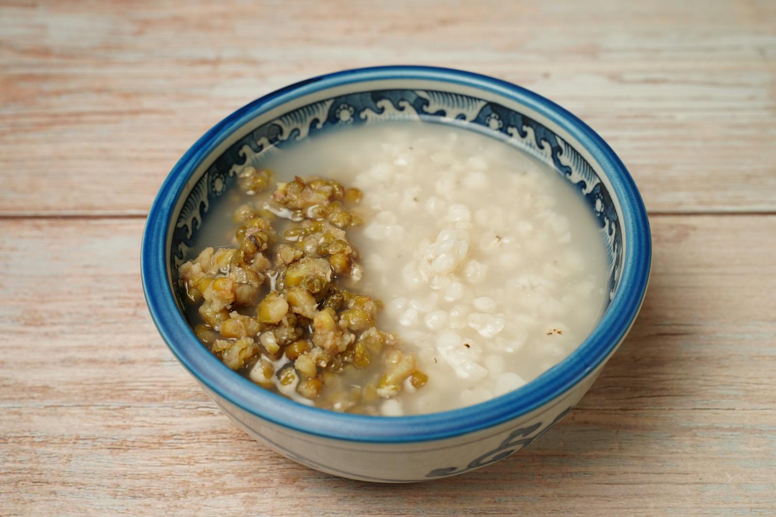 Close-up of cooked porridge in a blue and white ceramic bowl, similar in texture to cooked amaranth grain.