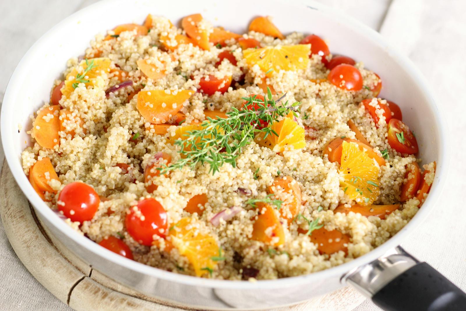 A bowl of cooked quinoa with fresh tomatoes, herbs, and citrus