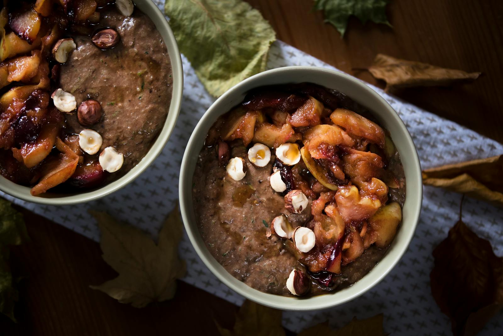 Warm bowl of cooked grain porridge topped with roasted fruit and hazelnuts