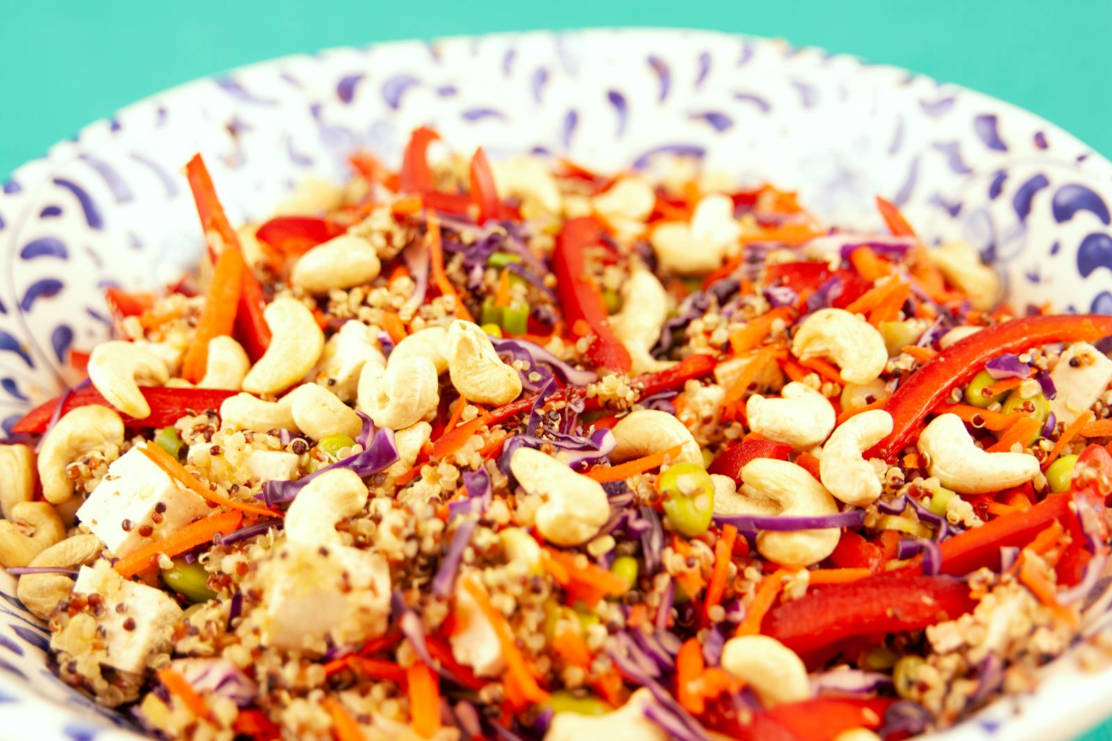 A colorful quinoa salad with red cabbage, cashews, and bell peppers in a ceramic bowl, the kind of straightforward gluten-free meal quinoa anchors.