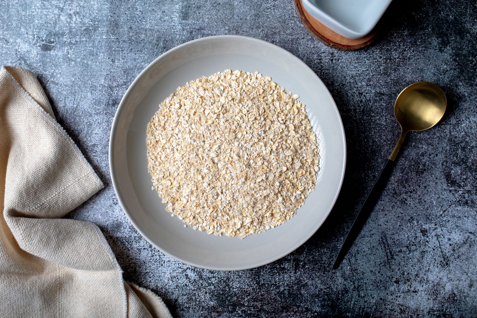 A bowl of cooked oat bran with a spoon on a linen cloth