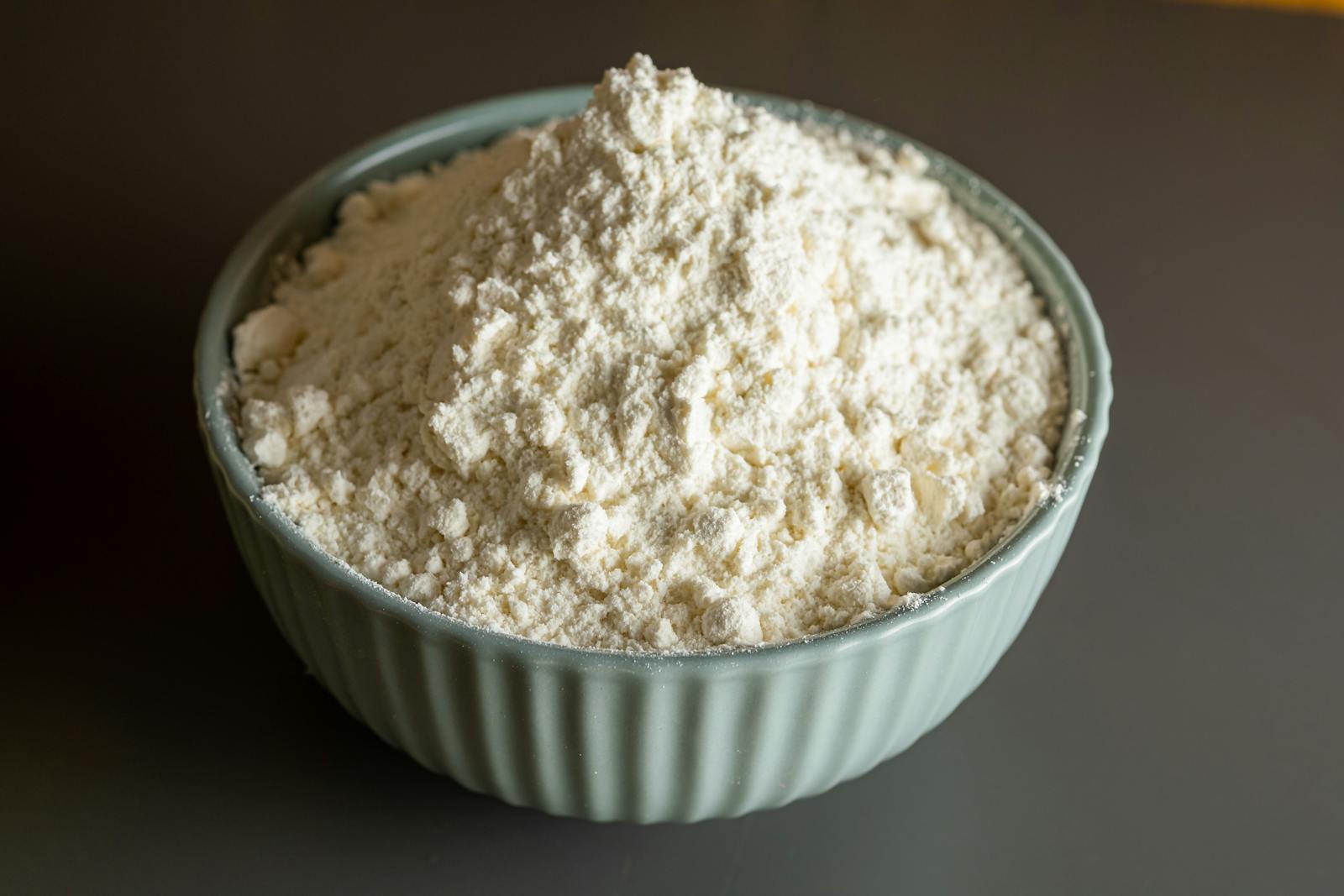 A close-up of pale, fine flour in a ceramic bowl, the cream colour and texture you would expect from properly milled quinoa flour.