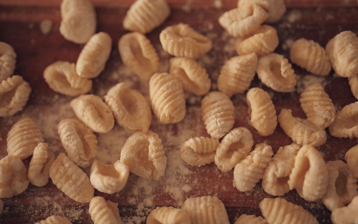Ridged semolina pasta dusted with golden semolina flour on a wooden board.