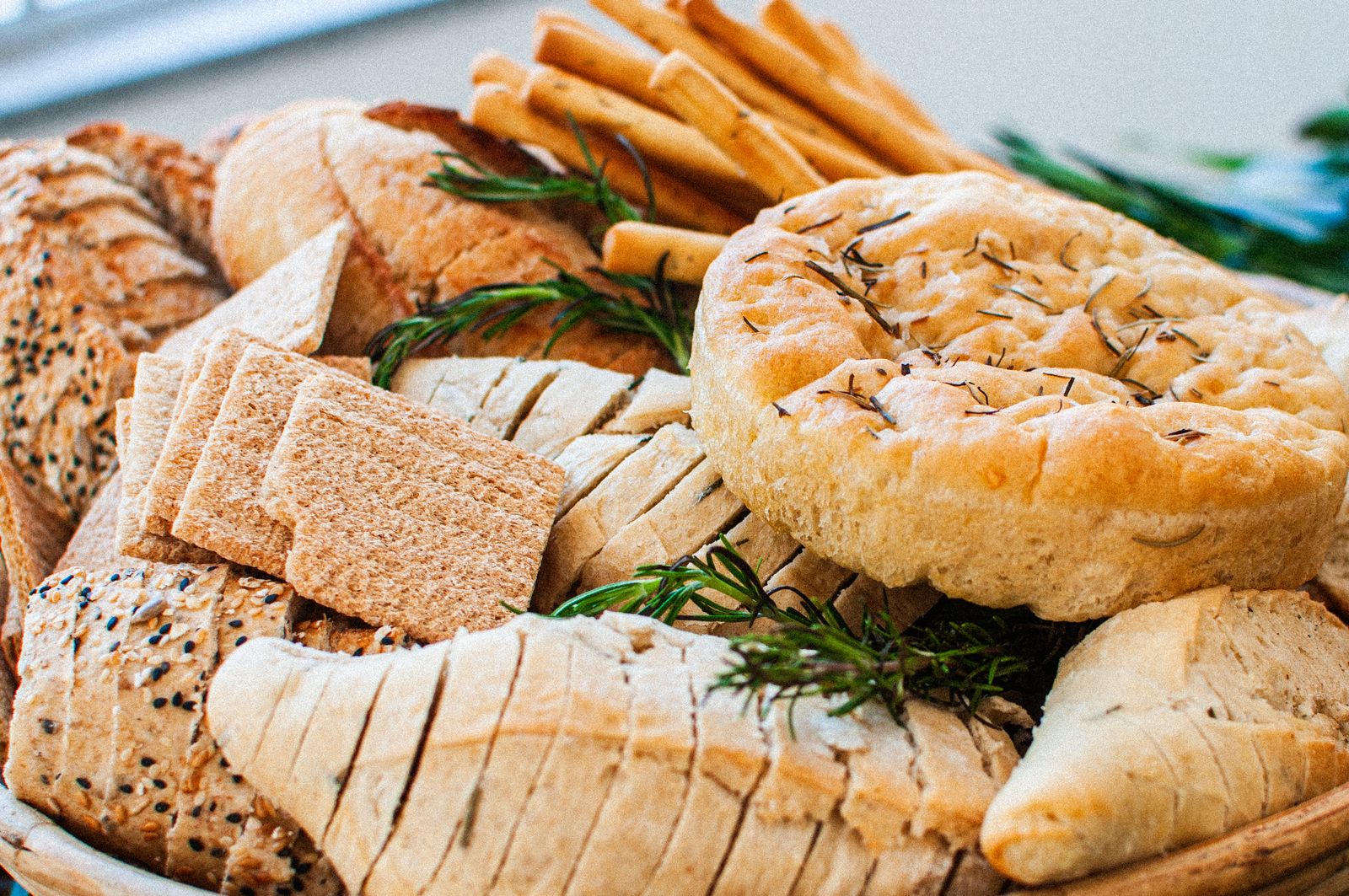 A variety of artisan breads and crackers garnished with fresh rosemary on a board