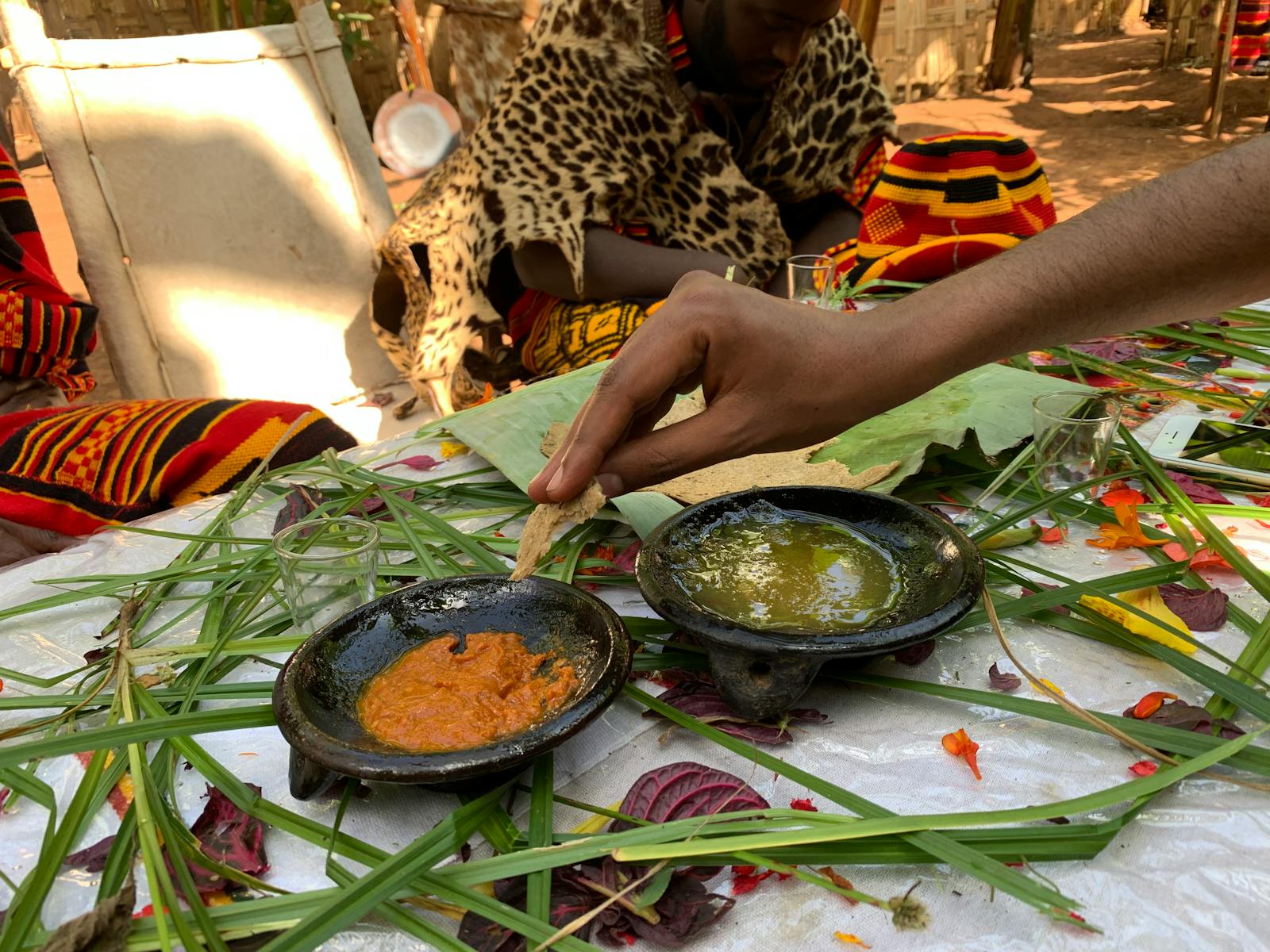 Hand preparing an Ethiopian dish with two sauces on colorful traditional textiles