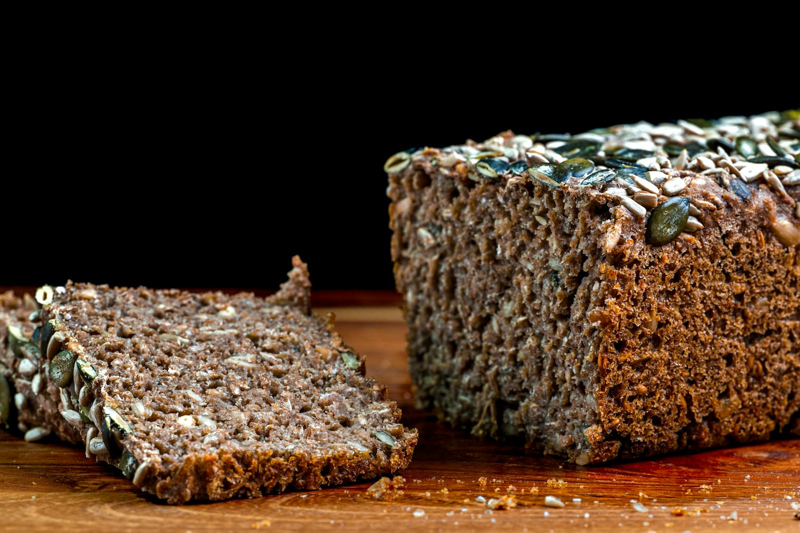 A close-up of sliced whole grain rye bread topped with sunflower and pumpkin seeds, the dense Danish-style loaf this recipe produces.